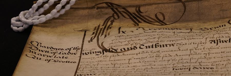 A close up image of a beautiful manuscript with white weights that look like pearls on the top left hand corner. 