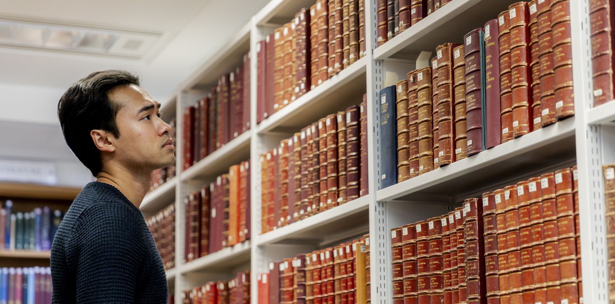 Someone looks at a row of bookshelves 